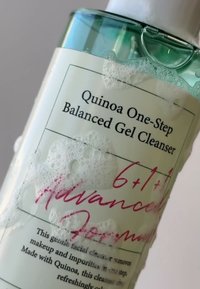Gel Nettoyant Équilibrant en Une Étape à la Quinoa dans un flacon transparent, avec un capuchon vert clair et des bulles mousseuses à la surface.