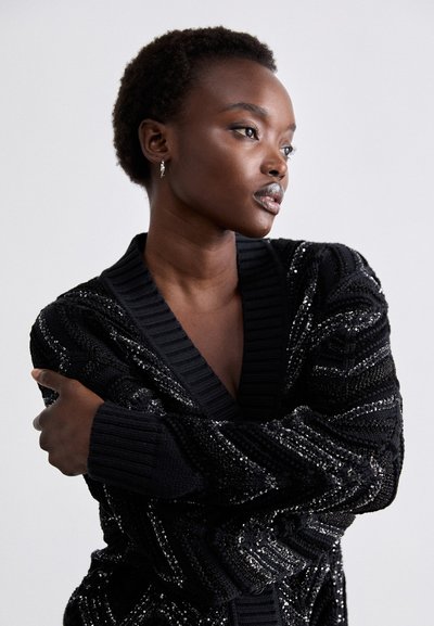 Μαύρο πλεκτό cardigan με βαθύ V-λαιμόκοψη και υφή ρίγας, στολισμένο με ασημένια στρας, διαθέτοντας ριμπ μανσέτες και στρίφωμα.