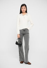 Hvid strikket sweater med krave, grå flagrende jeans med sidedele, sort håndtaske og sko med leopardprint.