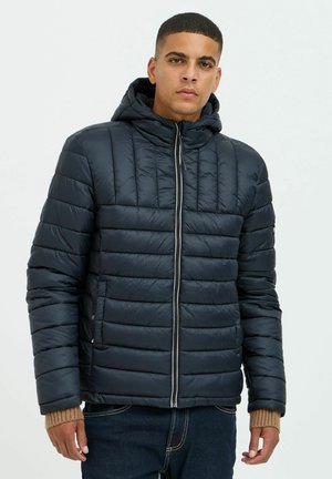 Puffer jacket in dark navy, featuring horizontal quilted sections, a hood, and a front zipper, with knit cuffs in a contrasting tan color.