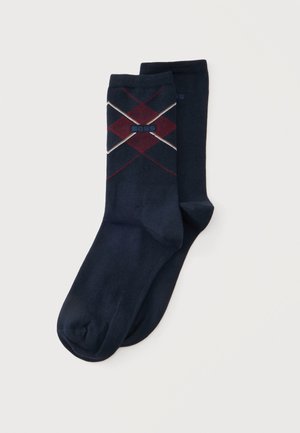 Paire de chaussettes habillées bleu foncé avec un motif losange rouge et beige et le mot "BOSS" sur la partie supérieure.