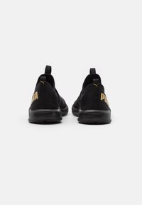 Baskets de sport noires au design épuré. Fabriquées en textile avec une tige texturée, elles arborent un logo Puma doré sur l'accent du talon.