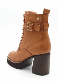 Brązowe skórzane botki za kostkę z masywnym drewnianym obcasem, sznurowanym przodem, bocznym paskiem z klamrą oraz wyściełanym kołnierzem dla większego komfortu.