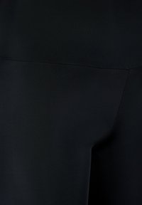 Leggings neri realizzati in tessuto liscio ed elastico. Presentano una vita a bassa altezza e cuciture minime, offrendo un aspetto elegante.