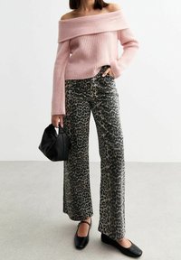 Maglione rosa a coste con spalle scoperte abbinato a pantaloni a gamba larga con stampa leopardata. Borsa nera e scarpe basse nere completano l'outfit.