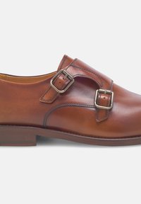 Braune Lederschuhe mit zwei verstellbaren Metall-Schnallen, runder Zehenform und dezenten Nähten. Glatte Textur und ein niedriger, gestapelter Absatz.
