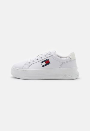 Biały niskoprofilowy sneaker z grubą podeszwą, sznurowaniem z przodu, naszywką z logo Tommy Jeans po boku oraz napisem „TOMMY” wytłoczonym na podeszwie.