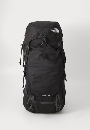 Mochila negra con un diseño espacioso, correas ajustables y bolsillos exteriores. Presenta la etiqueta "TERRA 55" en la parte inferior frontal.