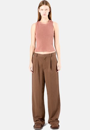 Brązowe spodnie z szerokimi nogawkami i zakładkami, zestawione z dopasowanym, prążkowanym topem w kolorze przybrudzonego różu. Gładki materiał o luźnym fasonie.
