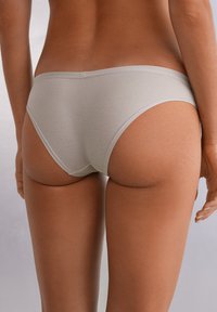 Grå bomullsbrief med en slät textur, medelhögt skuren och minimal design. Inga synliga mönster eller hårdvarudelar. Enkelt bakåtblick.