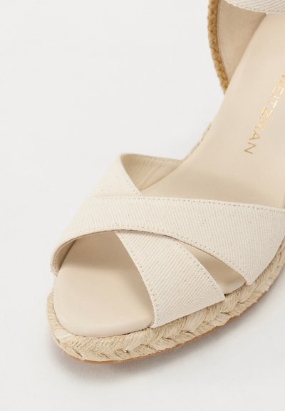 Hiekkabeige espadrille-sandaalit ristikkäin olevilla kangasvöillä ja punottu jutekanta. Silkkinen sisävuori ja hieman pyöristetty varvas.
