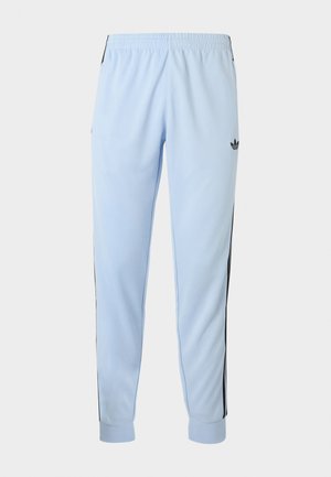 Lichtblauwe sportbroek met zwarte zijkstrepen, elastische tailleband, omgeslagen enkels en adidas-logo op de rechterdij.