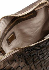 Bolso de mano de cuero marrón trenzado con una cremallera dorada semiabierta, que muestra un forro de tela beige y un bolsillo con cremallera interior.