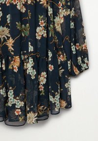 Kukallinen mekko tummansinisestä läpinäkyvästä kankaasta, jossa on röyhelöhelma, monimutkaisia kukkakuvioita kermaan, persikkaan ja teal-väriin, sekä kevyt rakenne.