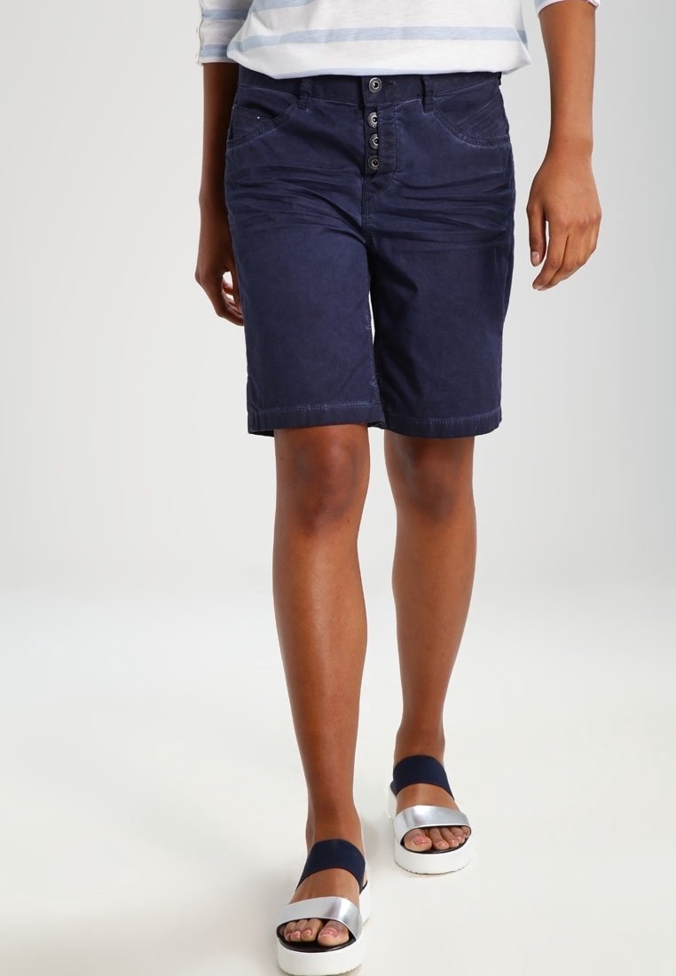 Navyblauwe katoenen shorts met een knoopsluiting en vijf zakken. Het ontwerp heeft een rechte snit en omgeslagen zoom, in combinatie met platform sandalen.