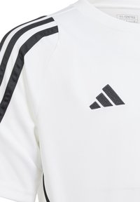 Hvid atletisk T-shirt med sorte tre-stribede detaljer på skuldrene og et sort broderet logo på forsiden. Glat stofstruktur.