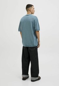 Polo surdimensionné en mélange de coton de couleur bleu clair, avec un col et des manches courtes. Associé à un jean en denim foncé à coupe décontractée avec des poignets retroussés.
