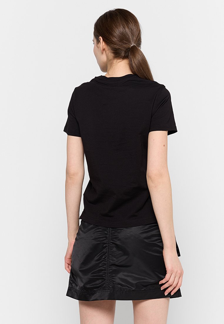 T-shirt di cotone nero con maniche corte e scollo rotondo, abbinato a una gonna nera in satin con dettagli arricciati sul retro.