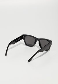 Ochelari de soare dreptunghiulari negri cu lentile întunecate. Fabricati din plastic lucios, cu brațe elegante și un hardware minim pe laturi.