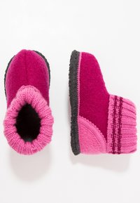 Roze vilten slippers met een gebreide bovenrand, met een contrasterende donkergrijze zool. Inclusief decoratieve strepen op de bovenrand en een textuur op het oppervlak.