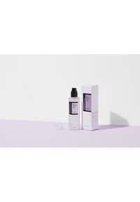 Bouteille en plastique transparente avec un couvercle à pompe noir, contenant un liquide transparent. Étiquette violette et noire avec du texte. Boîte blanche avec des accents violets.