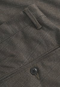 Tessuto intrecciato marrone con un sottile motivo, caratterizzato da una tasca frontale e un bottone nero con dettaglio del logo.