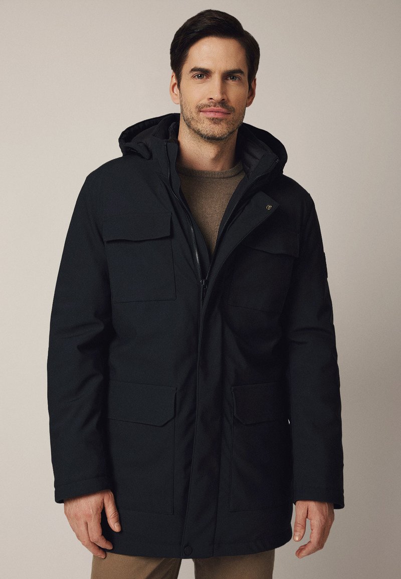 Czarna parka z kapturem, z zamkiem błyskawicznym, dwiema przednimi kieszeniami z klapą i teksturowanym wnętrzem. Idealna na zimne dni.