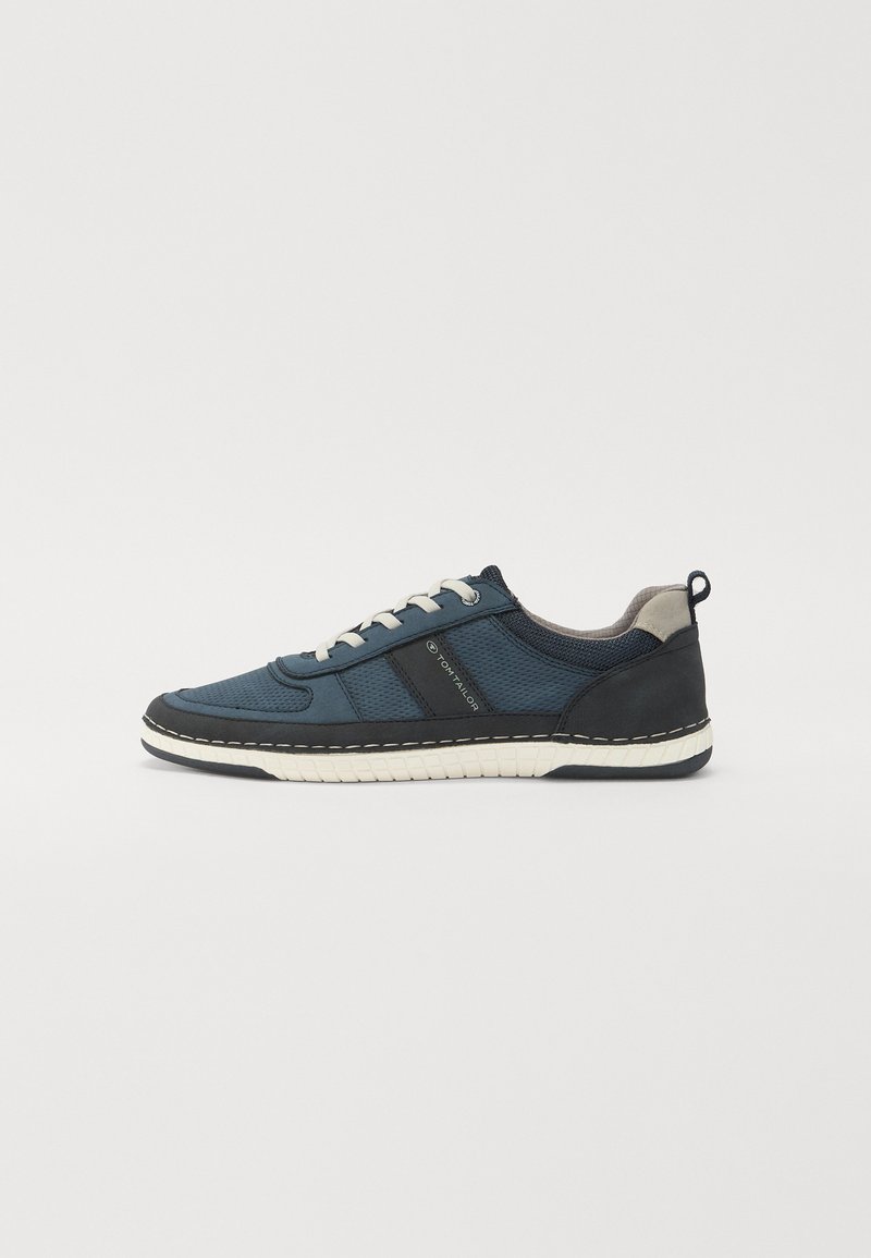Baskets de sport bleu marine en mesh et matériaux synthétiques, avec des lacets blancs, une tige texturée et une semelle en caoutchouc blanc avec des coutures.