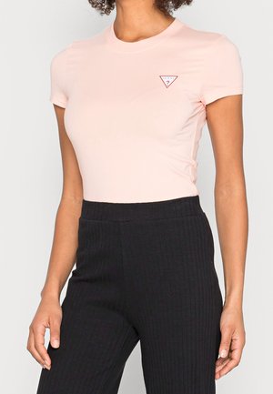 Lyserød tætsiddende t-shirt lavet af blødt stof, med et lille rødt og hvidt logo i triangel-form på brystet.