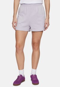 Shorts di cotone lilla con vita elasticizzata, caratterizzati da un design semplice e una texture liscia. Abbinati a sneaker viola e calze bianche.