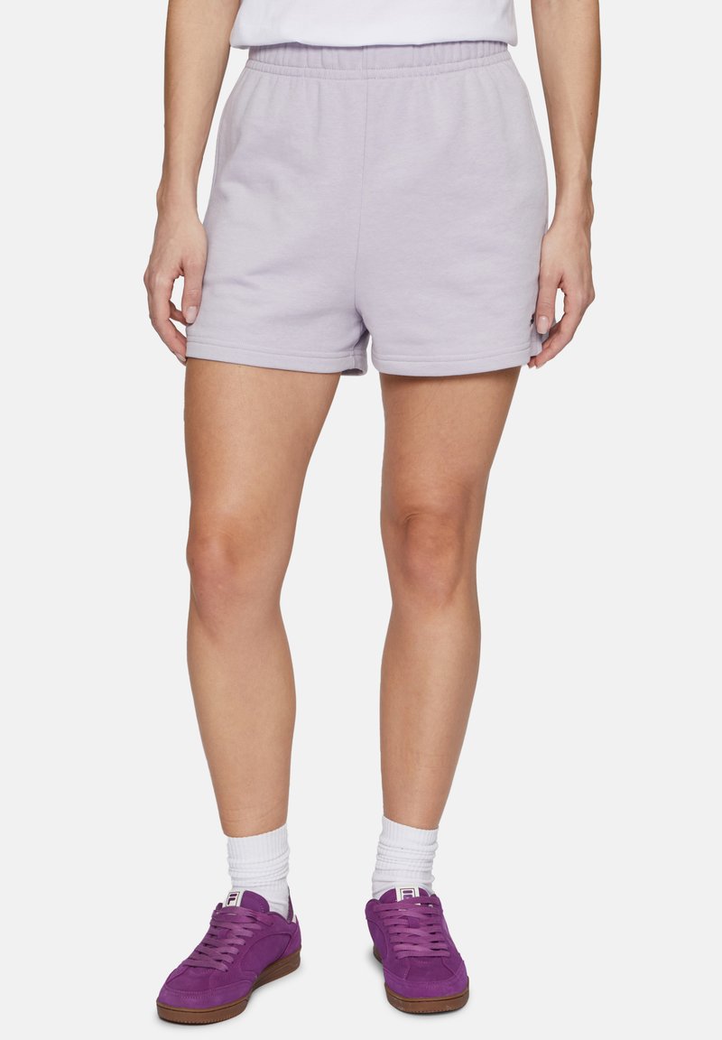 Shorts di cotone lilla con vita elasticizzata, caratterizzati da un design semplice e una texture liscia. Abbinati a sneaker viola e calze bianche.