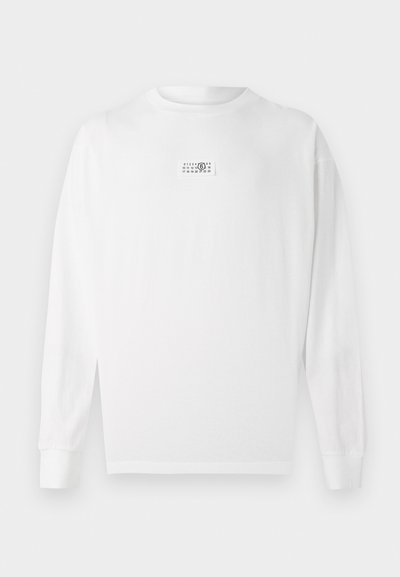Long-sleeve white T-shirt made of cotton, featuring a small graphic label on the chest and ribbed cuffs. Simple, straight-cut design.
