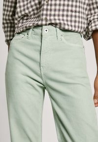 Mint green corduroy pants with a straight leg design, featuring front pockets, a button closure, and a textured fabric surface.