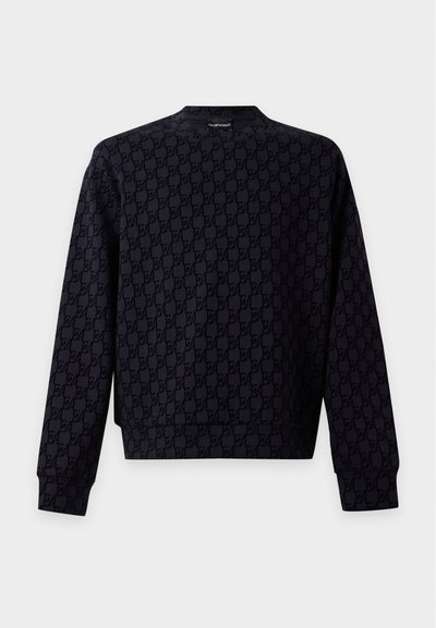 Sweat-shirt noir à manches longues avec un petit motif de logo sur l'ensemble et des poignets côtelés, présenté sur un fond uni.