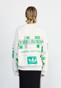 White sweatshirt featuring green and gray graphic patterns, text “THE ACES” and “RYETOWN TENNISCLUB,” and Adidas logo on the back.