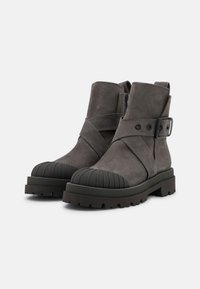 Šedé kožené kotníkové boty s zaoblenou gumovou špičkou, detailem pásku a strukturovanou podrážkou. Obsahují zipové zapínání a robustní design.