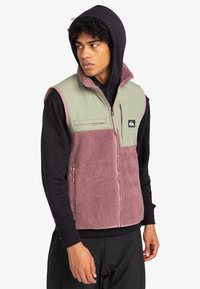 Fleece-Weste in Grün und Mauve mit Reißverschluss, zwei Taschen und einem Logo-Patch. Verfügt über einen hohen Kragen und ein ärmelloses Design.