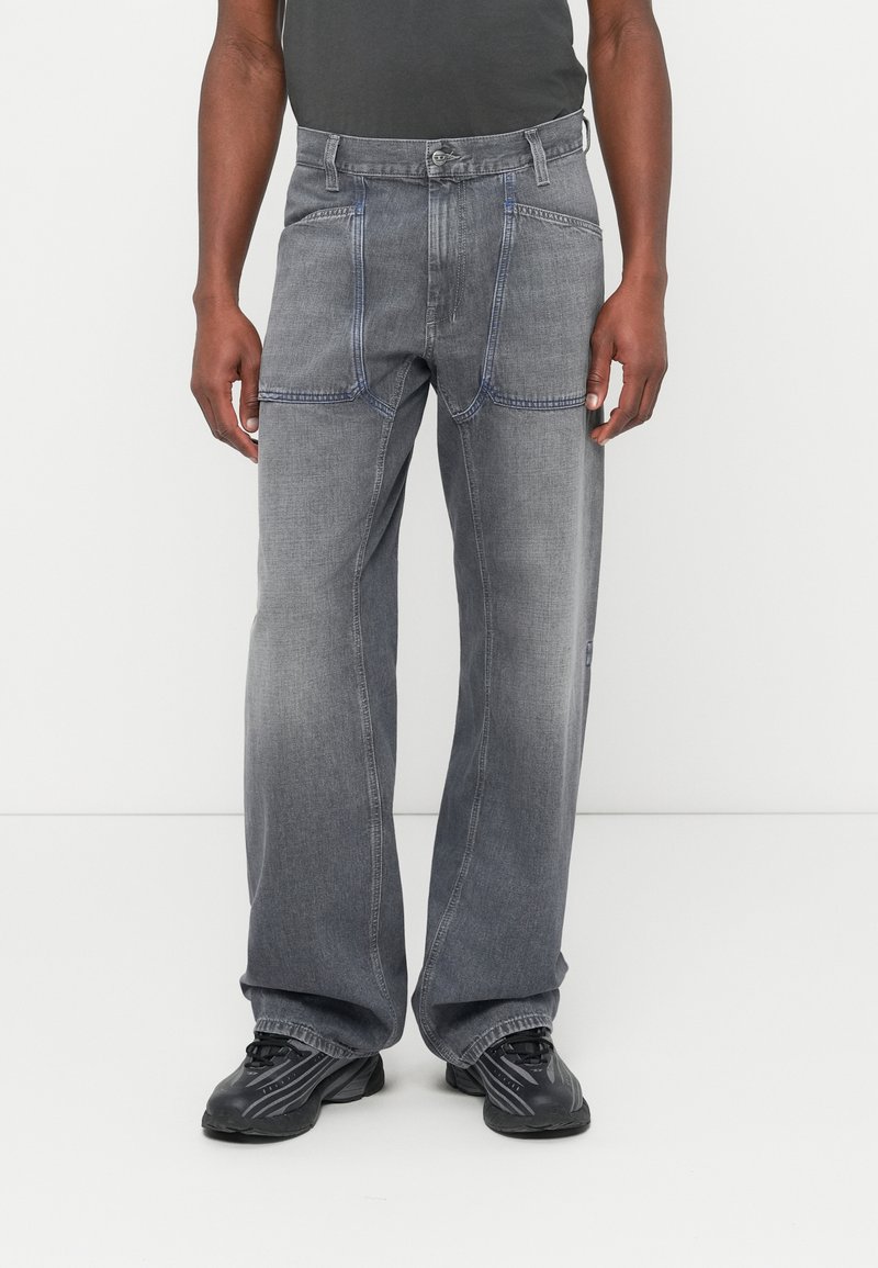 Jeans in denim grigio con vestibilità ampia, caratterizzati da cuciture blu a contrasto, cinque tasche e una classica chiusura con bottone in vita.