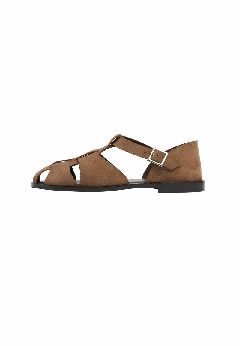 Sandal in scamosciato marrone con design a ritaglio, cinturino alla caviglia regolabile con fibbia in metallo, suola piatta nera e punta aperta.