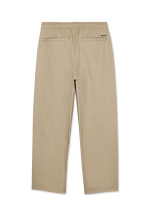 Pantalon beige à taille élastique avec poches passepoilées à l'arrière et une petite étiquette noire sur le côté droit, présenté à plat sur un fond blanc.