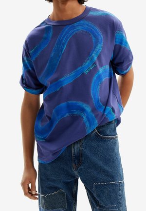 T-shirt graphique bleu avec motifs de vagues sur fond violet, à manches courtes et col rond, en coton.