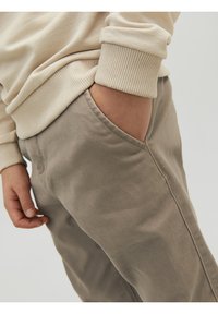 Beige sweatshirt med ribbade ärmar som matchas med ljusgrå byxor med sidoficka, tillverkade av mjukt tyg med en slät yta.