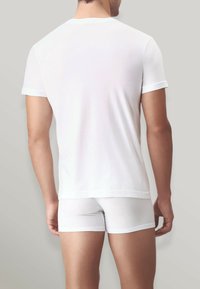 T-shirt bianco a maniche corte e boxer bianchi, aderenti, in tessuto morbido, design semplice, bordi senza cuciture, vista da dietro.