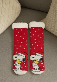 Calzini rossi con pois bianchi, con un morbido polsino bianco e un'immagine di Snoopy che indossa un cappello da Babbo Natale. Realizzati in morbido materiale a maglia.