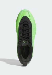 Grønne og sorte atletiske sko med en tekstureret overdel, glat tåhætte og sorte snørebånd; fremhævet med et logo på tungen.