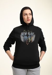 Sudadera negra con un gráfico que presenta "Music Television NUEVA YORK" y diseños de alas. Tiene un bolsillo canguro en la parte frontal y capucha con cordón.