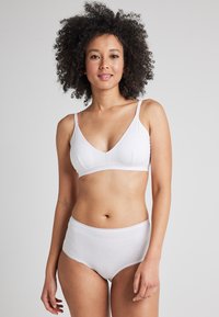 Bralette de algodón blanco con tirantes ajustables y copas suaves, combinado con braguitas de algodón blanco de talle alto. Diseño simple y sin costuras.