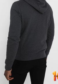 Felpa con cappuccio grigia scura con tasca a marsupio, polsini a costine e cappuccio con coulisse. Realizzata in tessuto morbido, presenta un design aderente.