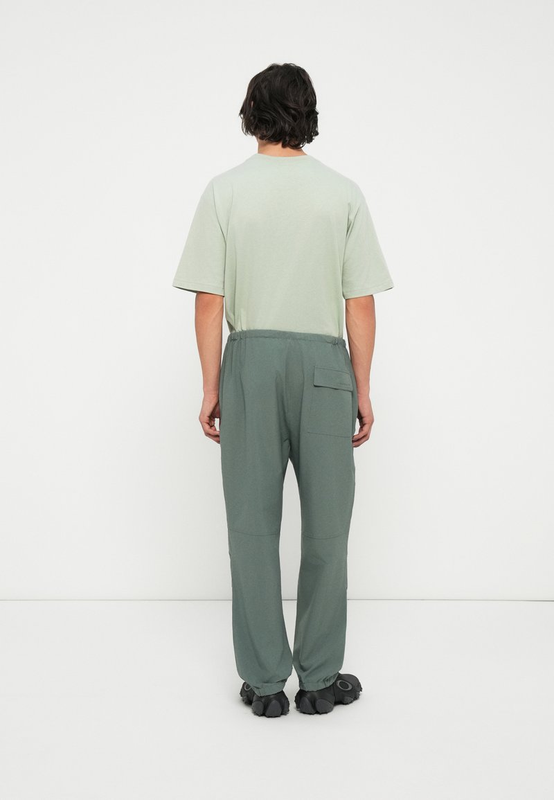 Chemise à manches courtes vert clair et pantalon large vert foncé à taille élastique. Le pantalon présente une poche latérale et une texture douce.