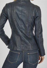 Námořnicky modrá kožená bunda s přiléhavým střihem, vertikálními švy a malým límcem. Hladká textura s mírným leskem a upraveným siluetou.